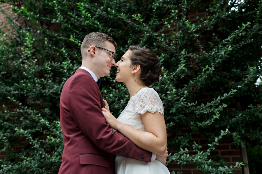 A bride and groom kiss in front of an ivy wall in south Philadelphia.